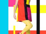 Colorful concept in sixties retro fashion style with Caucasian model posing full body over designed background with colorful bright stripes and color blocks.